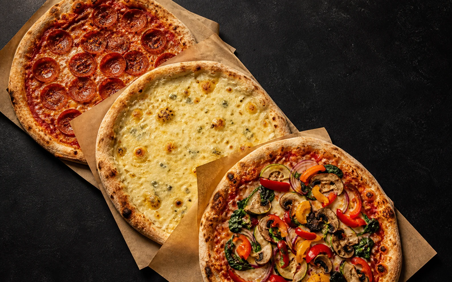 Drei unterschiedliche Pizzen frisch aus dem Ofen